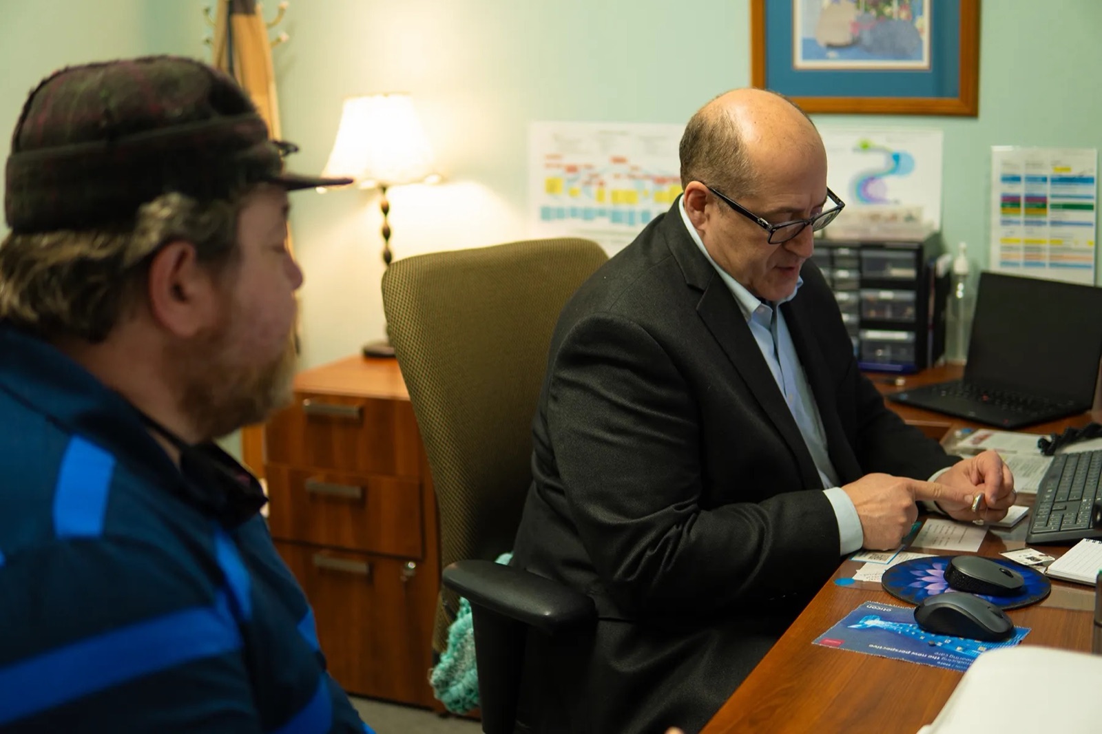 Dr. Fosco at his desk, going over hearing aid details with a patient